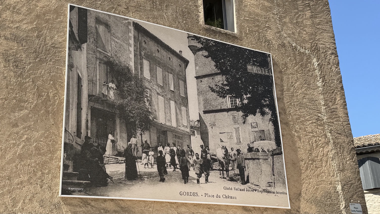 Oude foto van de Place du Château op een gevel in Gordes