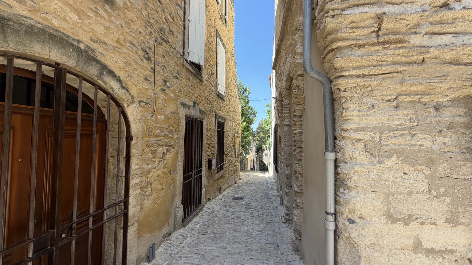 Smalle geplaveide steeg tussen natuurstenen huizen in Gordes